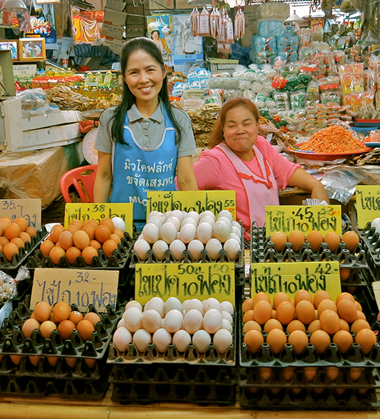 Happy faces selling eggs at a Khorat street market.